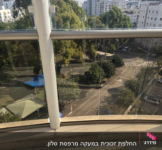 מעקה זכוכית שקוף מותקן במרפסת דירה המשקיפה לפארק